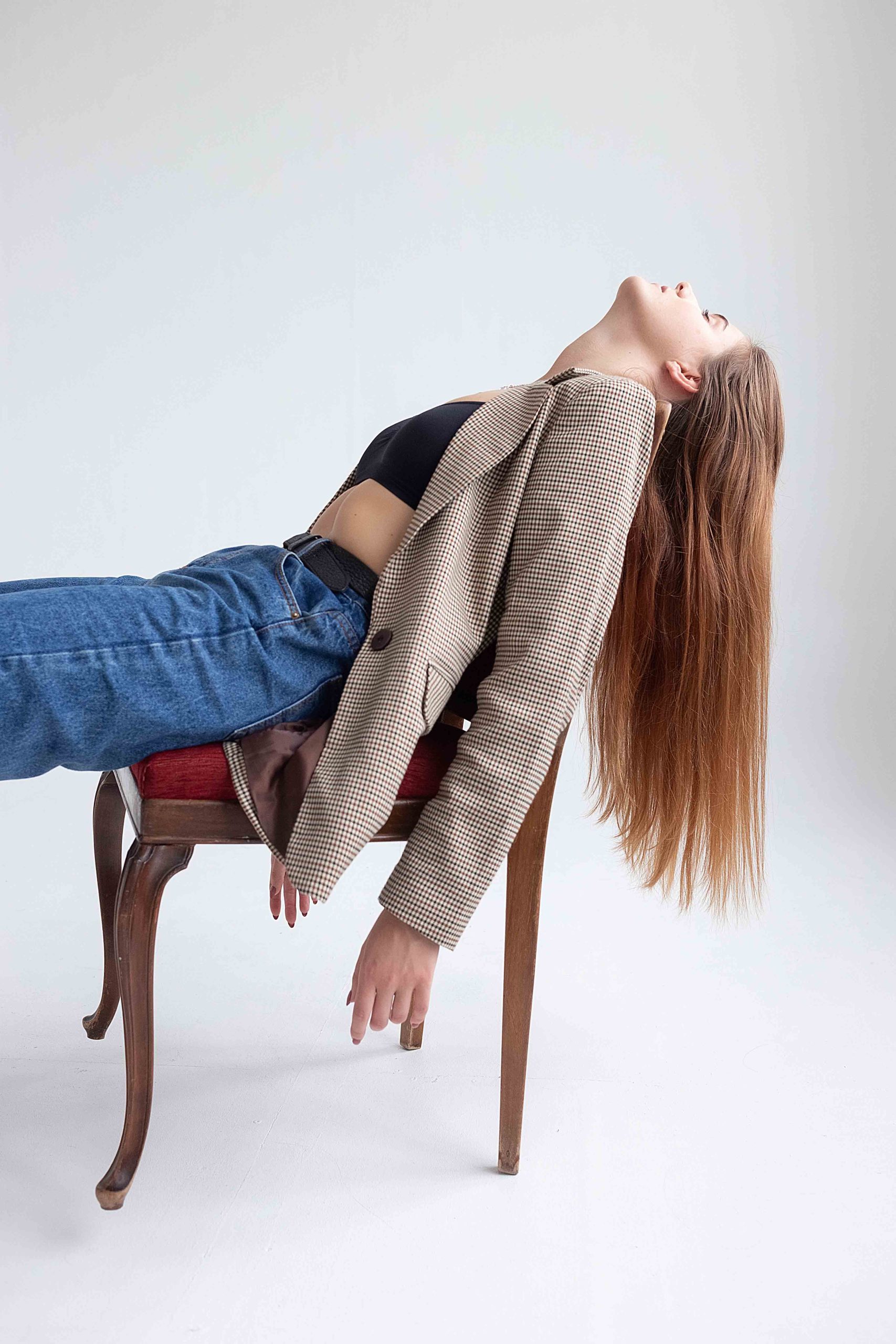 young caucasian woman with long hair lying on chair at studio with her chin up